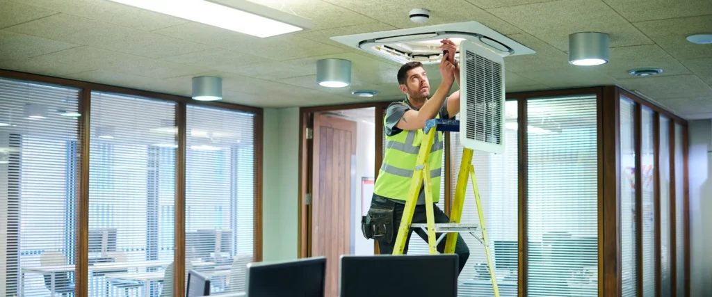 Technician on a ladder servicing an air conditioner
