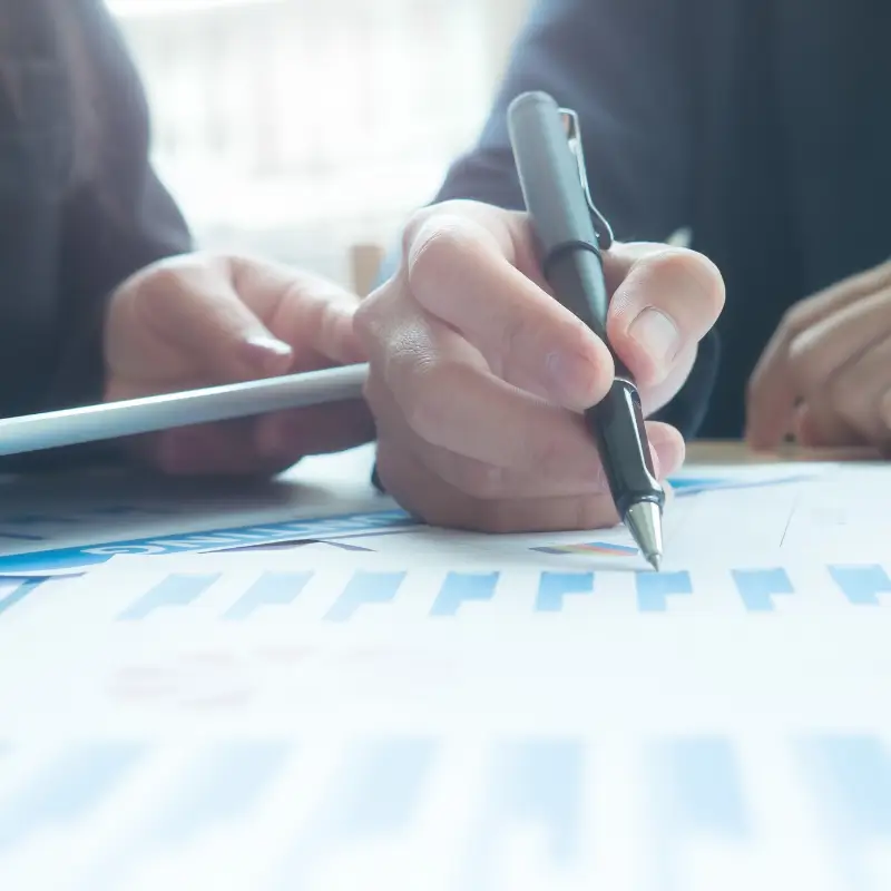 Hand holding a pen and pointing to a chart